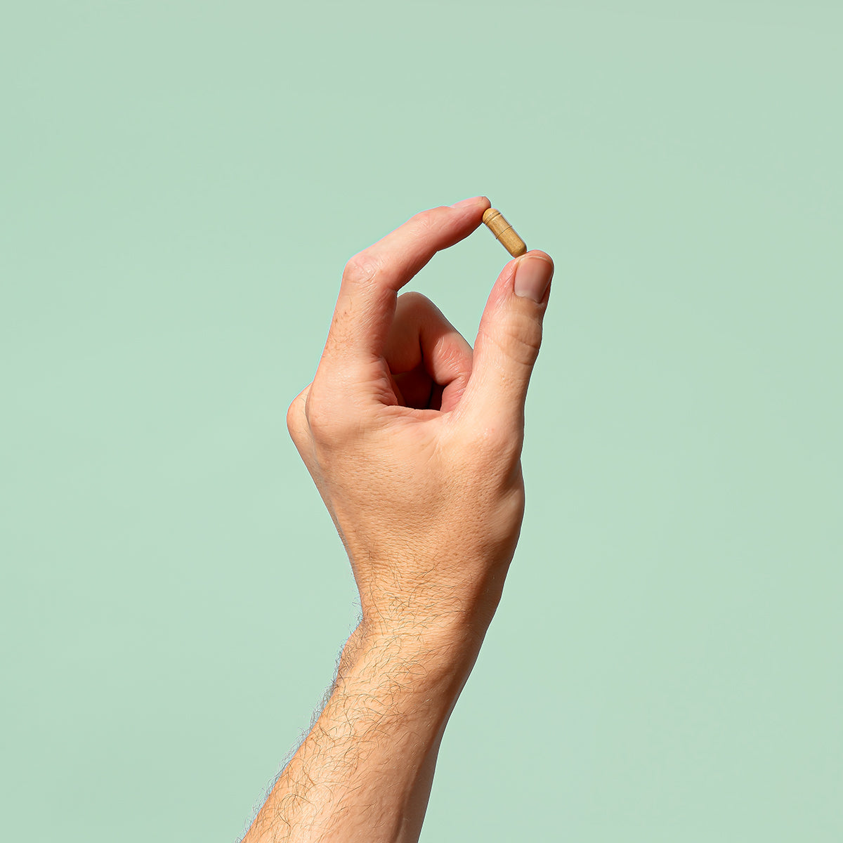 Man holding a Good Hair Multivitamin between thumb and index fingers